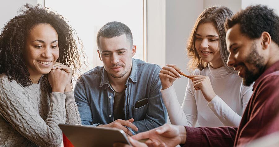 várias pessoas sentadas próximas olhando para notebook e conversando sobre seguro de vida em grupo